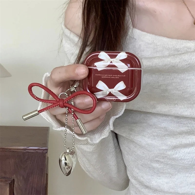 Bow AirPods case with love charm held in hand, scale reference