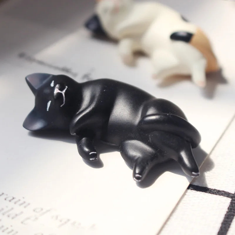 Kawaii resin sleeping cat figures beside a pencil for scale reference