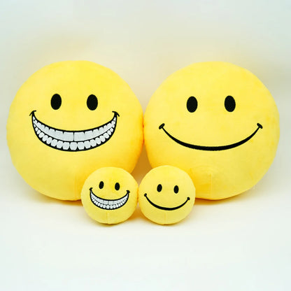 Soft yellow smiley face plush stress ball held in two hands showing size reference