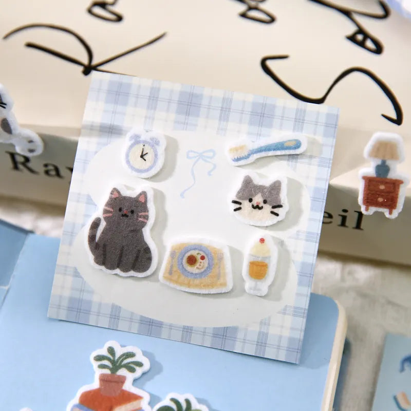 Felt kawaii cat stickers decorating a planner page with handwritten notes
