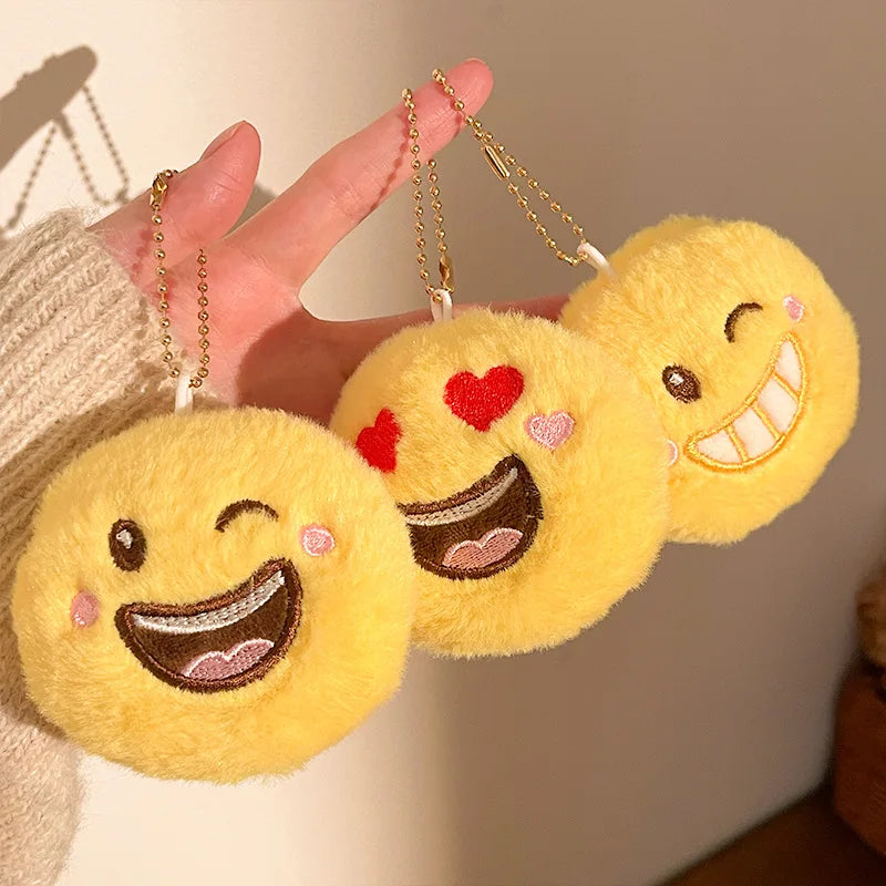 Close-up of kawaii plush emoji keychain pendant showing soft fabric and embroidered smiley face