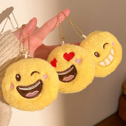 Close-up of kawaii plush emoji keychain pendant showing soft fabric and embroidered smiley face