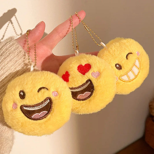 Close-up of kawaii plush emoji keychain pendant showing soft fabric and embroidered smiley face