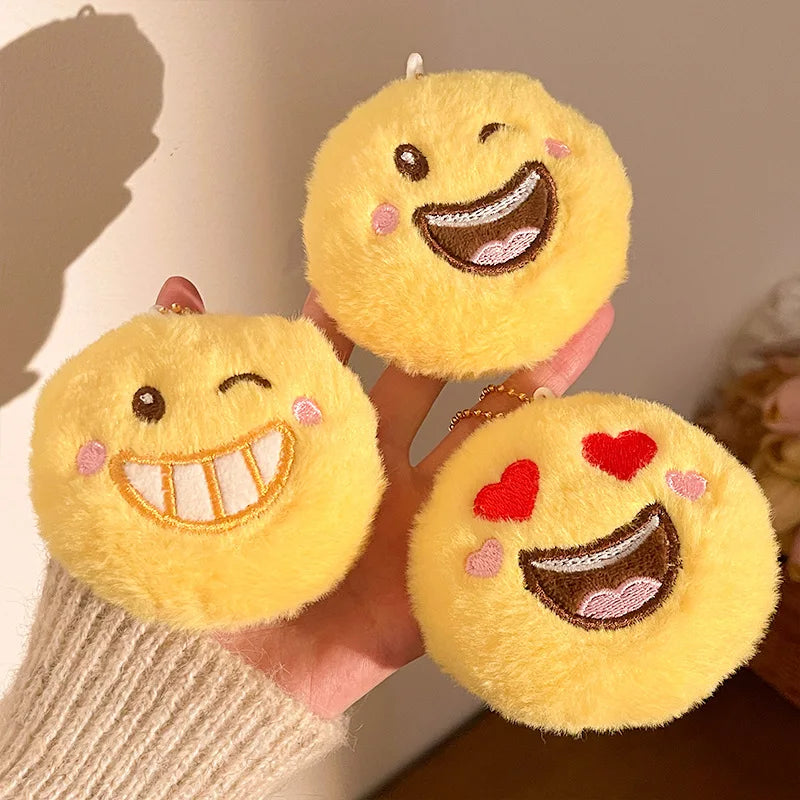 Kawaii plush smiley face bag charm clipped to a tote bag zipper pull in daily use